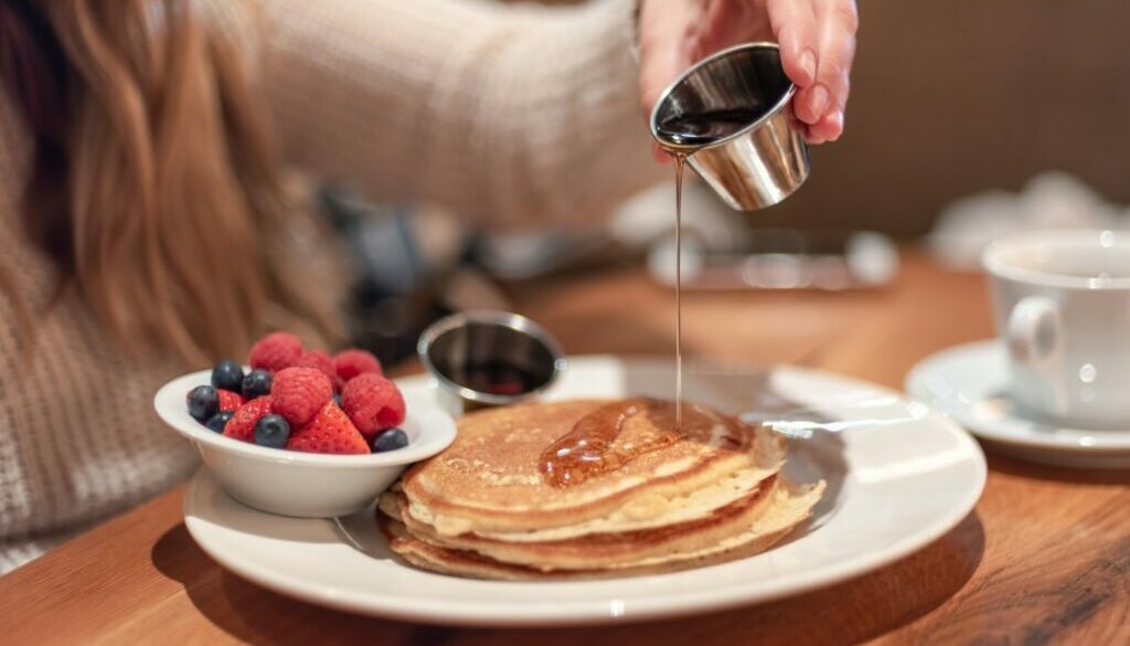meeting-friends-for-breakfast-young-woman-pouring-warm-maple-syrup-on-pancakes_t20_pR7238