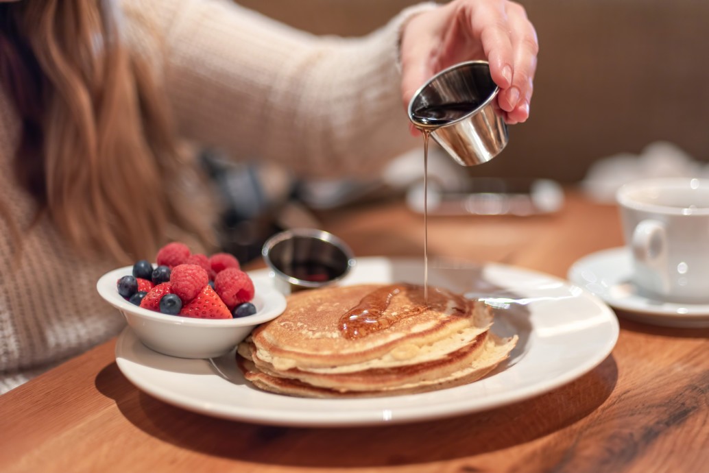 meeting friends for breakfast young woman pouring warm maple syrup on pancakes t20 pR7238